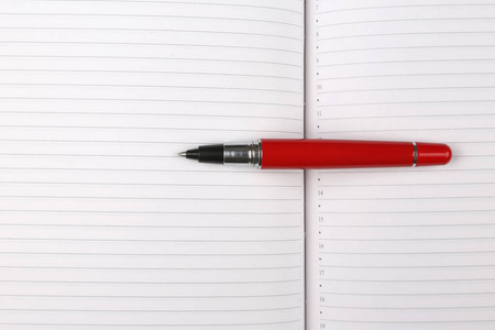 躺在打开笔记本上的红钢笔