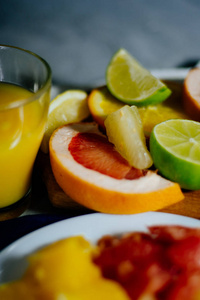 各种各样的柑橘水果切成切片橙 柚 柠檬 葡萄柚 石灰一杯橙汁。铺在木板和背景上的老式白板