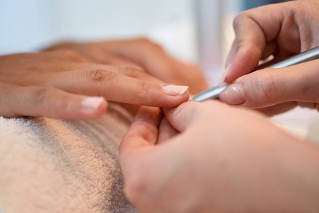 在沙龙中的指甲退化的妇女接受修指甲由美容师与指甲文件