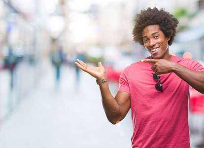 非裔美国男子在孤立的背景下惊讶和微笑的相机, 而提出与手和手指指着