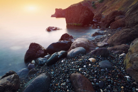 在日落的海景。美丽的自然海景，在长时间曝光。石头在前景