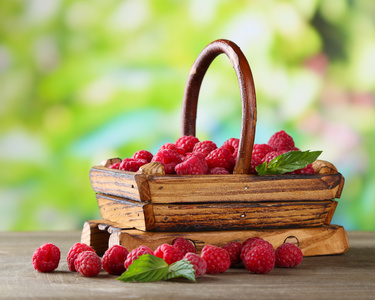 成熟甜树莓在木桌上，在绿色背景上篮