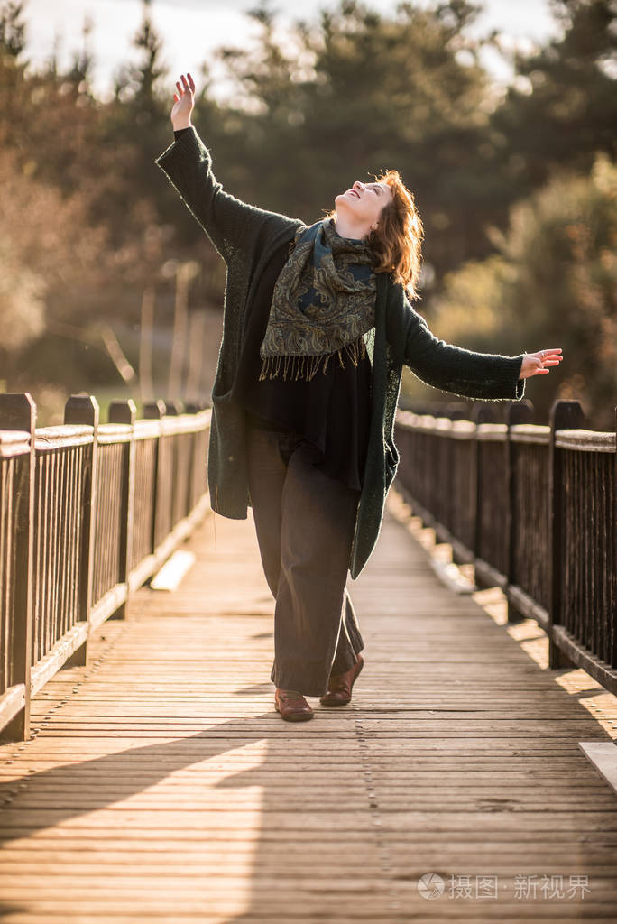 快乐的女人在森林里的一座木制的旧桥上摆姿势, enjoyin