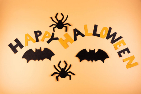 一个快乐的万圣节标志创建的彩色纸和装饰使用两个蜘蛛和两个黑蝙蝠。橙色背景