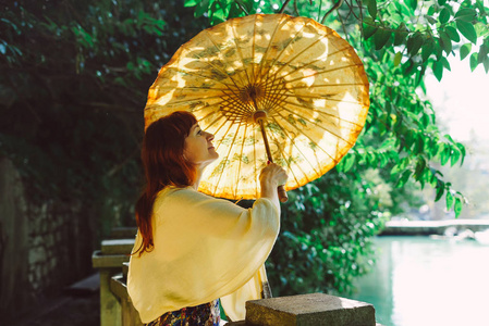 迷人的 redhaired 女孩在一条黄色的围巾周围散步公园, 在手中的中国雨伞
