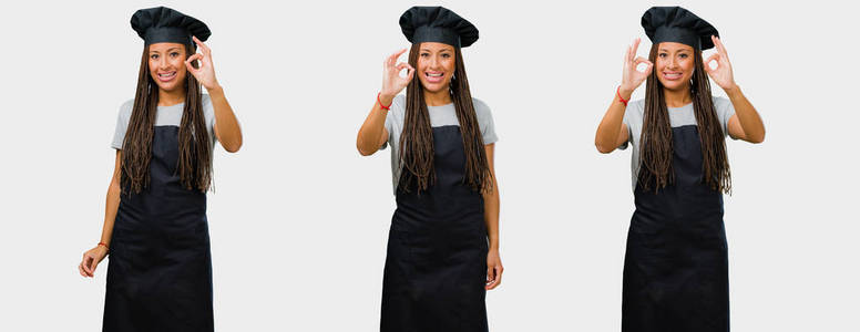 一套年轻的黑人女性面包师在黑色制服开朗和自信做 ok 手势