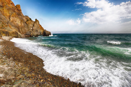 海浪在岸边撞击, 在海滨鹅卵石上流淌。岩石海滨