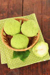 桑橙果实 maclura pomifera 在篮子里，木制的背景上