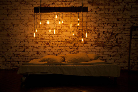 漂亮舒适的阁楼风格的房间。卧室的大床和白色的床单, 上面的灯
