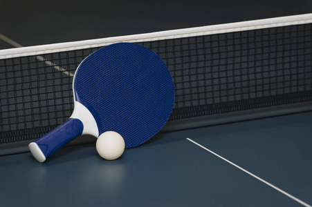 乒乓球拍和球和网在蓝色乒乓球桌上