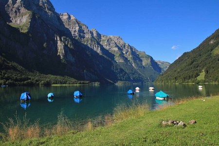 Klontalersee 湖的绿草甸。钓鱼船和山脉 Glarnisch。夏天场面在瑞士