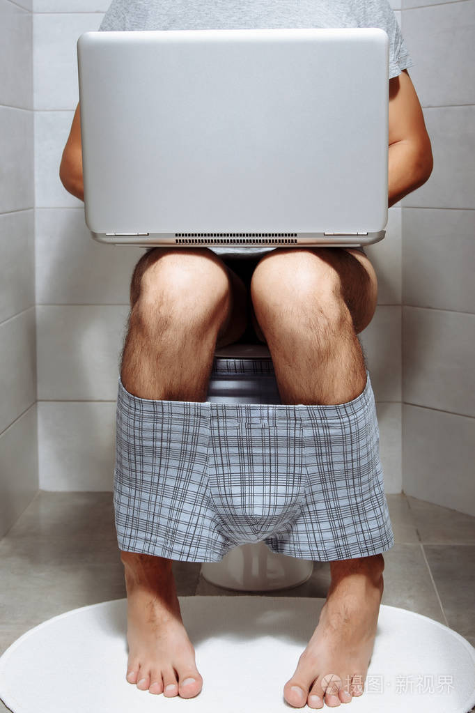 用笔记本电脑关闭坐在马桶上的男人