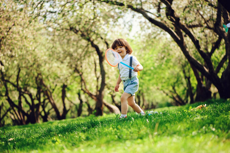 快乐的3岁男孩在阳光明媚的花园或公园里走着网, 捉.