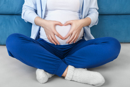 怀孕的妇女，用手在肚子上心的形状