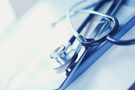 蓝色心血管医疗设备: 白色背景的蓝色听诊器和片剂.医疗设备照片