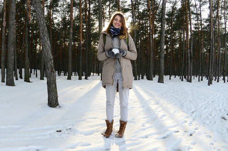 一个年轻而快乐的白种女孩穿着棕色大衣, 冬天在白雪覆盖的森林里举行雪球。鱼眼照片