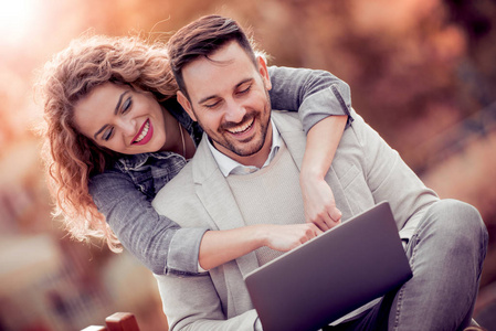年轻夫妇使用笔记本电脑户外和寻找快乐
