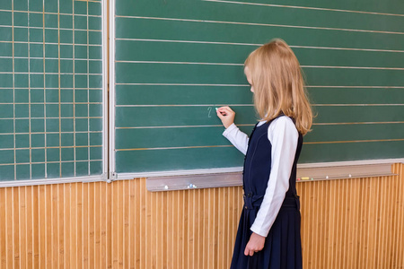 小学一年级学生在绿色黑板上写的女孩在学校课上