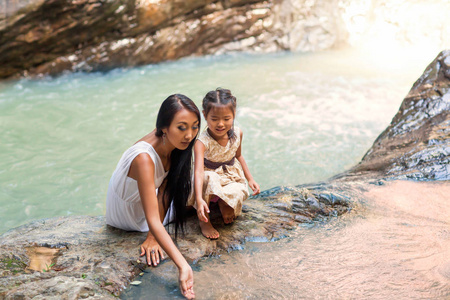 快乐的母亲与她的女儿在热带附近的瀑布。母亲节