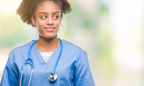 年轻的美国黑人医生妇女在孤立的背景微笑着看一边, 凝视着远离思考