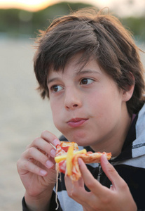 男孩在海滩吃意大利比萨
