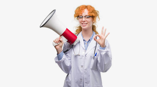 年轻红发医生的女人手持扩音器做 ok 标志与手指, 优秀的符号
