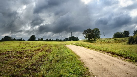 绿色的原野和路反对风雨如磐的天空