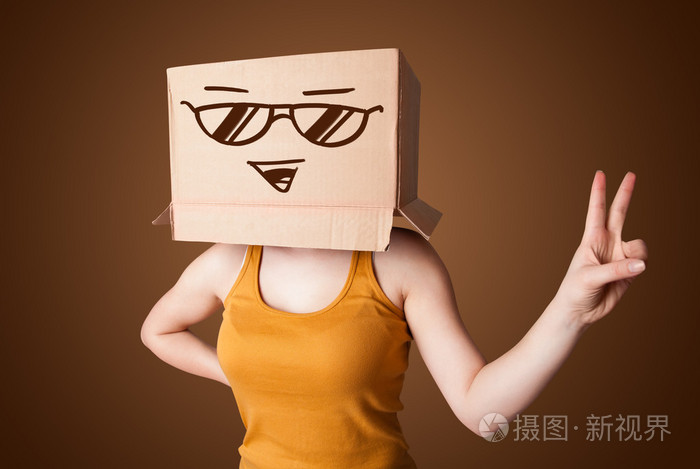 打手势用纸箱带笑容的她头上的年轻女士
