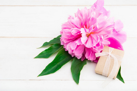 迷你礼品盒与丝带和粉红色的花朵在木质背景