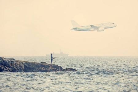 海滩上的渔夫男孩在看飞行飞机