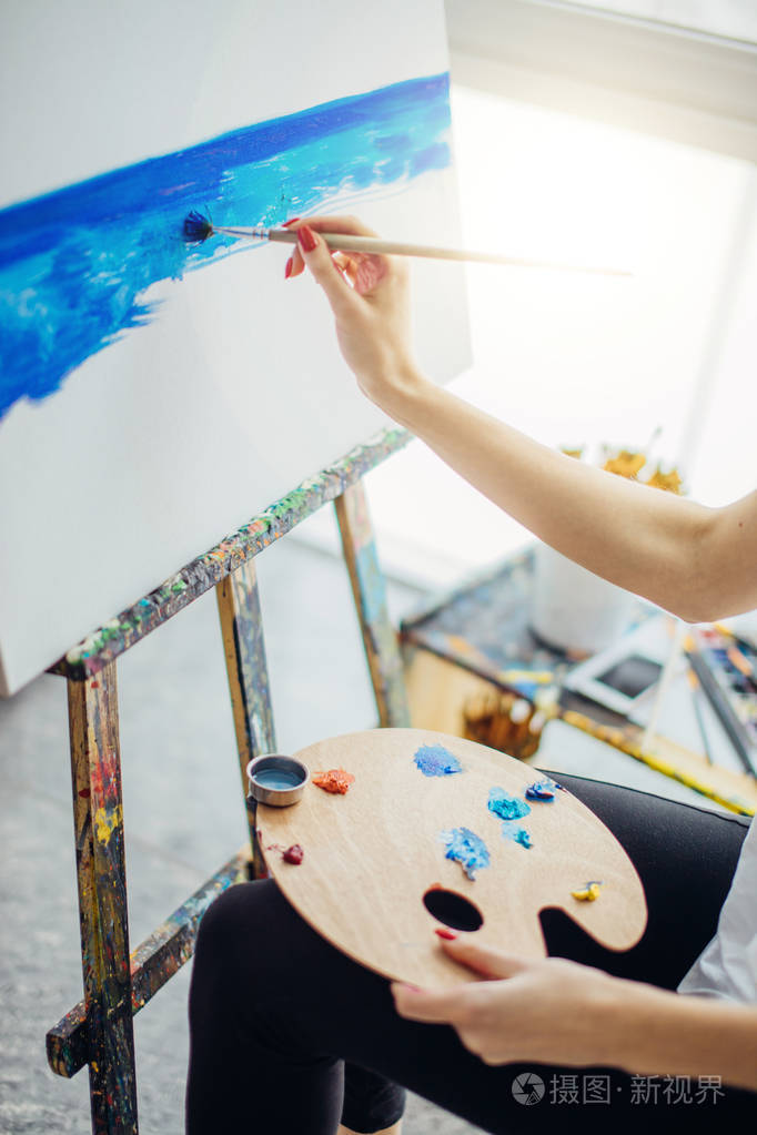 女画家在灯光明亮的画室里画一幅画