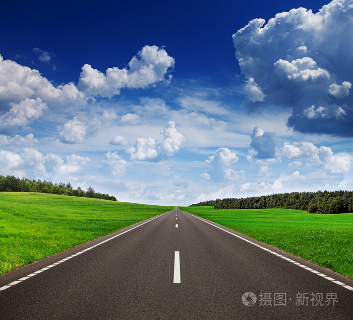 在绿色的田野,美丽的天空下的沥青路面