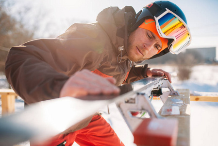 男滑雪者在滑雪前检查滑雪板, 冬季主动运动