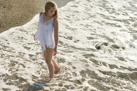 年轻女子走在白色的沙滩上