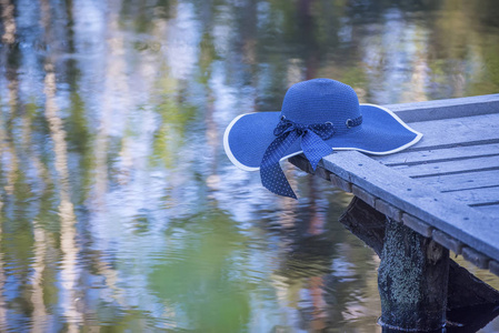 湖上一座木桥上的蓝色帽子。水中森林的美丽倒影。一个僻静的森林湖泊。安静和放松的气氛