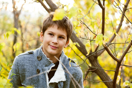 可爱的, 年轻的, 时髦的小男孩的肖像在树之间的灰色大衣。走在明亮的黄色秋天自然。家庭室外