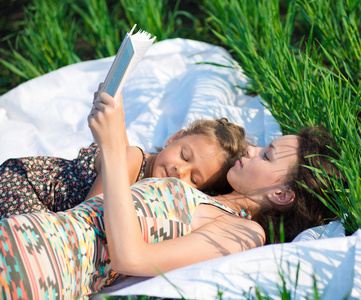 在绿色草地上读书的快乐女孩