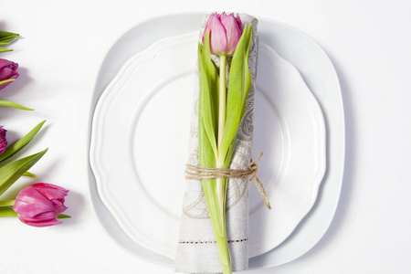 情人节贺卡。婚礼桌的装饰。在盘子里放着一张带有郁金香的餐巾, 漂亮的绑