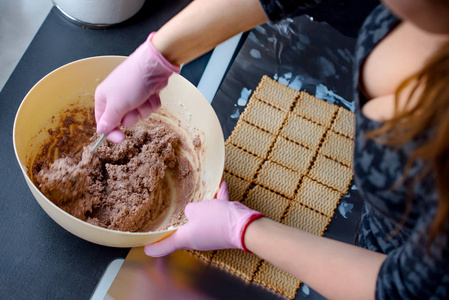 粉红色手套的妇女准备自制蛋糕, 她在塑料碗里搅拌面团