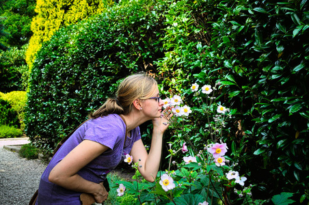 年轻女人闻在花园里的花朵