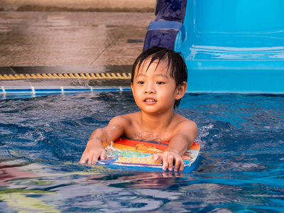 亚洲男孩正在游泳池里玩棋盘