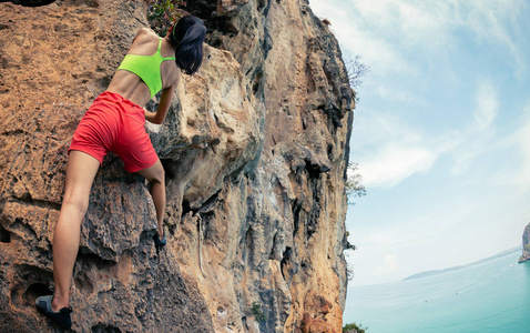 攀登海边悬崖的女子攀岩者