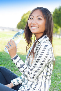 在一个公园的漂亮亚洲女孩饮用水