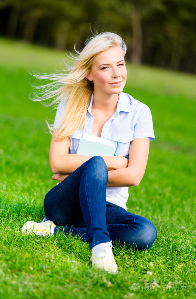 学生坐在绿色的草地上照片-正版商用图片06nk6a-摄图新视界