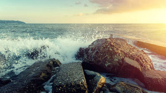 浪在 Ccoastal 的石头上破碎 , 在地平线和日落时变成泡沫海