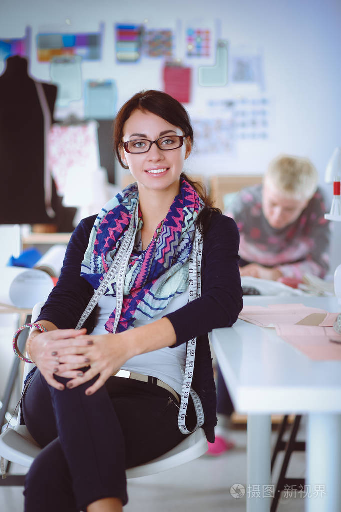 坐在桌子前工作室的美丽时装设计师