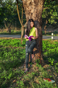 女人在树上 stading, 在公园里看书。