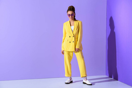 紫色太阳风暴微笑的非洲裔美国女孩摆在黄色西装和紫色的太阳镜, 在