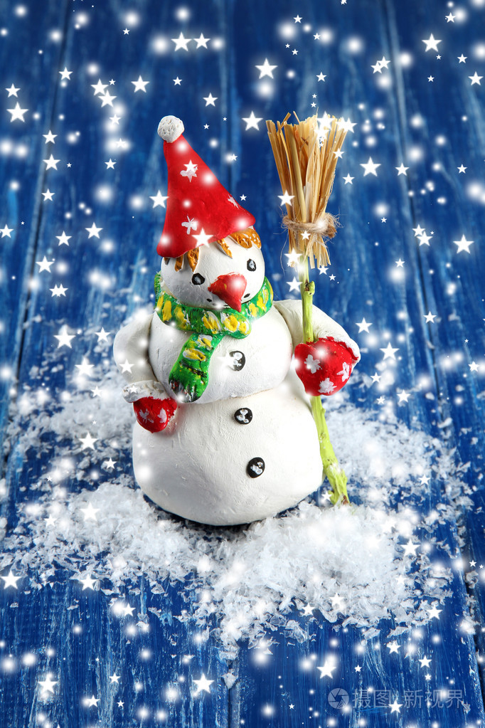 漂亮的雪人站在蓝色木背景上