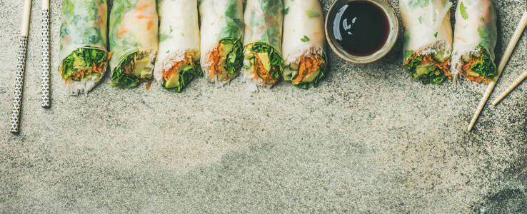 健康的亚洲美食。纯素食春, 夏米纸卷配蔬菜, 酱油, 筷子超过具体背景